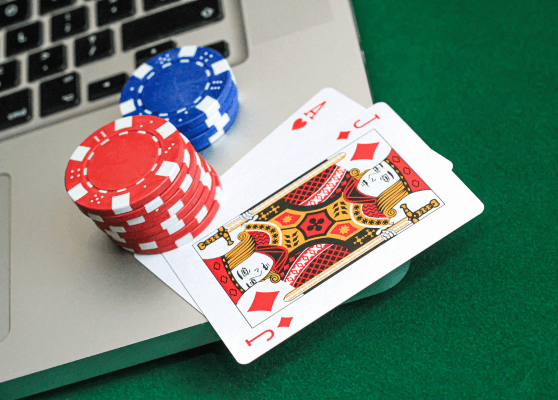 poker chips and a laptop on a green table